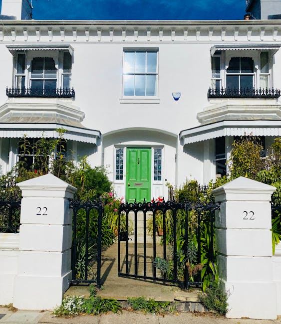 The image depicts the entrance to a period brick townhouse with a deep red front door, surrounded by white decorative architectural trim, situated at the top of a short flight of concrete steps. To th